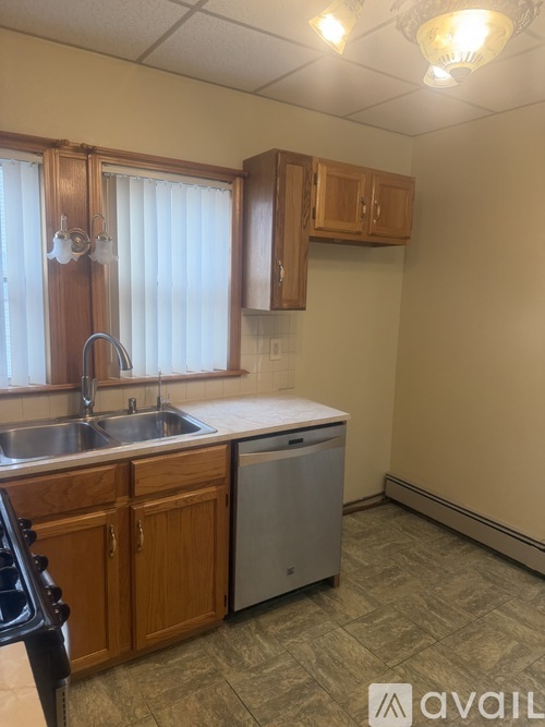 A kitchen with wooden cabinets and a stainless steel dishwasher.