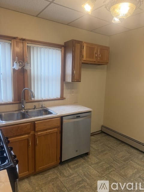 A kitchen with wooden cabinets and a stainless steel dishwasher.