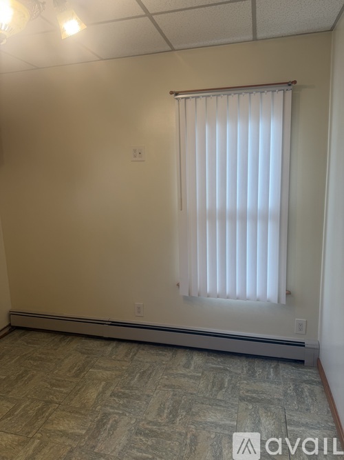 A room with a window covered by a white blind.