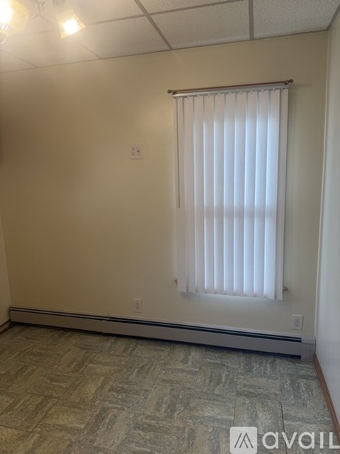 A room with a window covered by a white blind.
