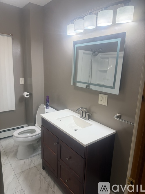 A bathroom with a toilet, sink, and mirror.