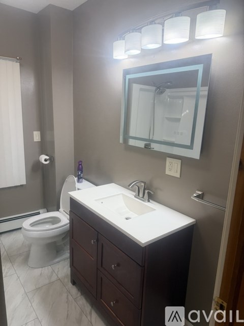 A bathroom with a toilet, sink, and mirror.