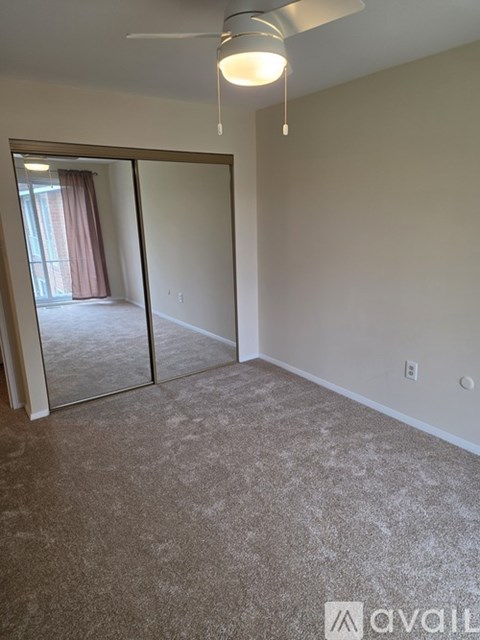 A room with a carpeted floor and a ceiling fan.