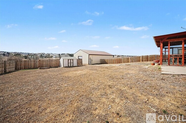 A large, empty field with a building and a wooden fence.
