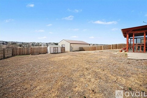 A large, empty field with a building and a wooden fence.