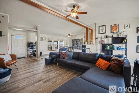 A living room with a grey couch and a ceiling fan.