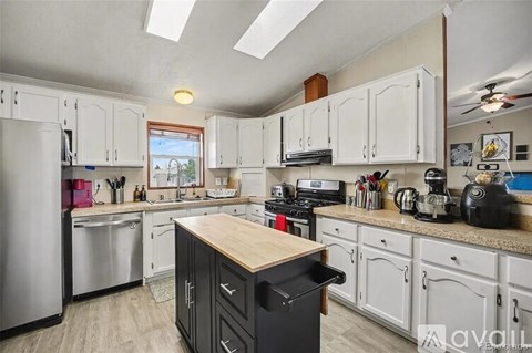 A kitchen with white cabinets and a wooden island.