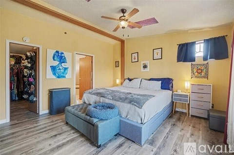 A bedroom with a bed, dresser, and a ceiling fan.