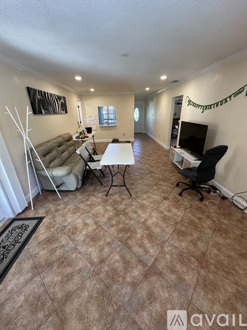 A living room with a couch, chairs, and a television.