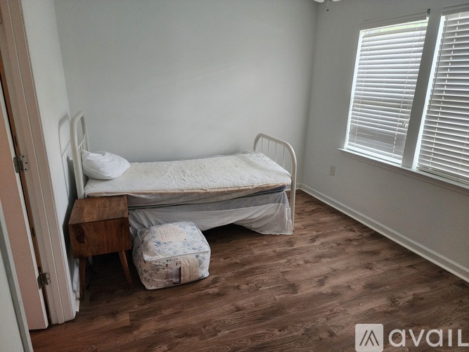 A bedroom with a bed, wooden nightstand, and a chair.