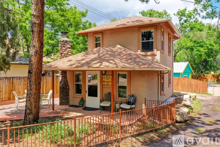A house with a brown roof and a porch with white chairs.