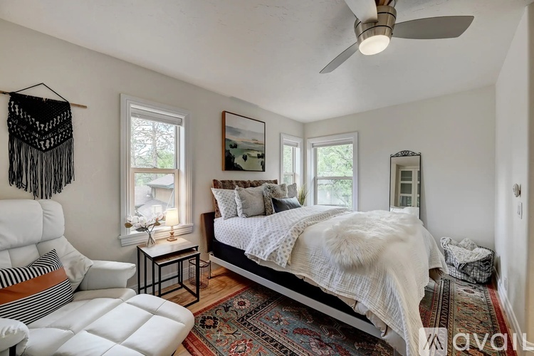 A bedroom with a bed, a chair, and a rug.