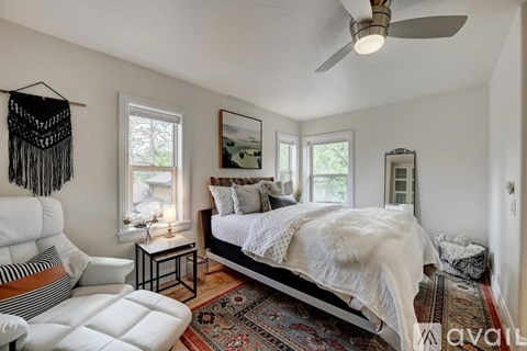 A bedroom with a bed, a chair, and a rug.