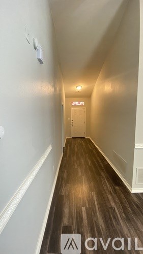 A hallway with wood flooring and white walls.