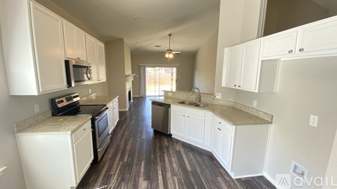 A kitchen with white cabinets and a wooden floor.