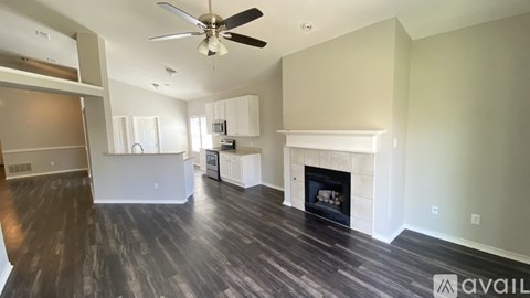 A spacious living room with a fireplace and a ceiling fan.