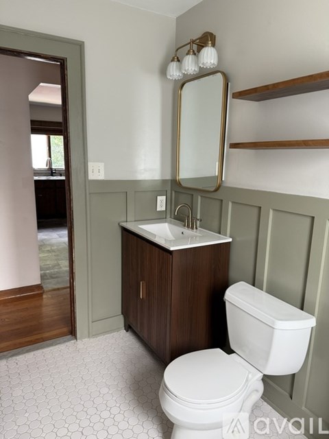 A bathroom with a toilet, sink, and mirror.
