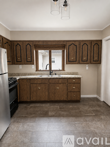 A kitchen with brown cabinets and a marble countertop.