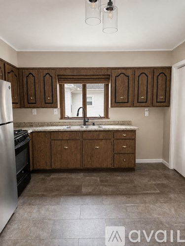 A kitchen with brown cabinets and a marble countertop.