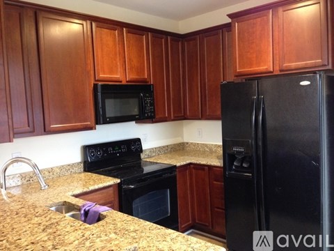 A kitchen with brown cabinets and black appliances.