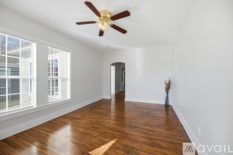 A room with a ceiling fan and wooden flooring.