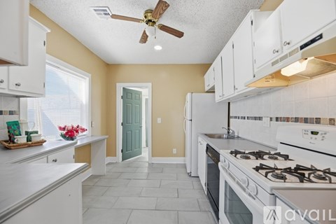 A kitchen with white cabinets and a white stove top oven.