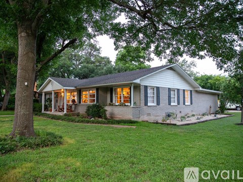 A house with a porch and a tree in front of it.