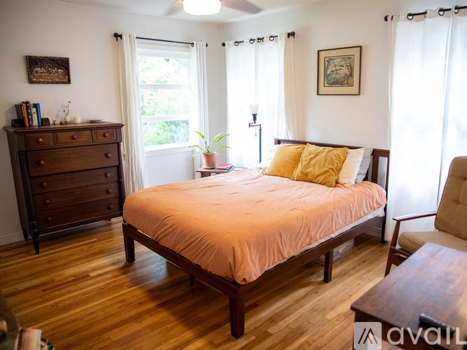 A bedroom with a bed, dresser, and window.