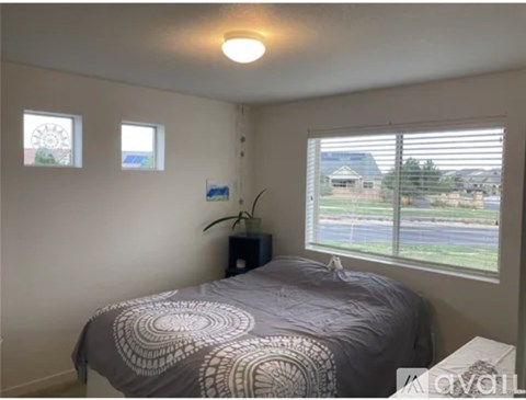 A bedroom with a bed, a nightstand, and a window with blinds.