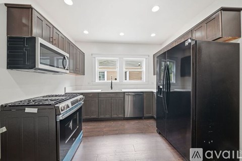 A kitchen with a black refrigerator, stove, and microwave.