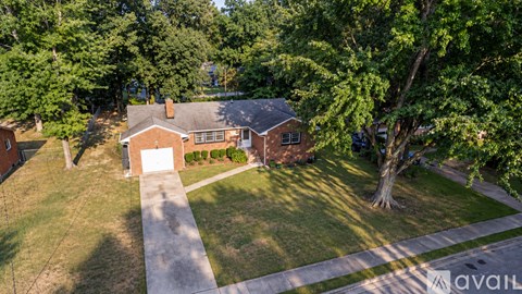 A house with a garage is surrounded by trees.