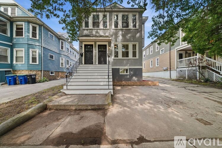 A house with a grey front yard and a blue trash can.