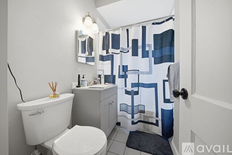 A bathroom with a white toilet, a white sink, and a shower curtain with blue and white designs.
