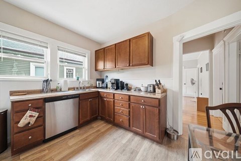 A kitchen with wooden cabinets and a stainless steel dishwasher.