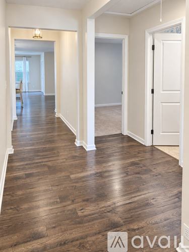 A hallway with wood flooring and white walls.