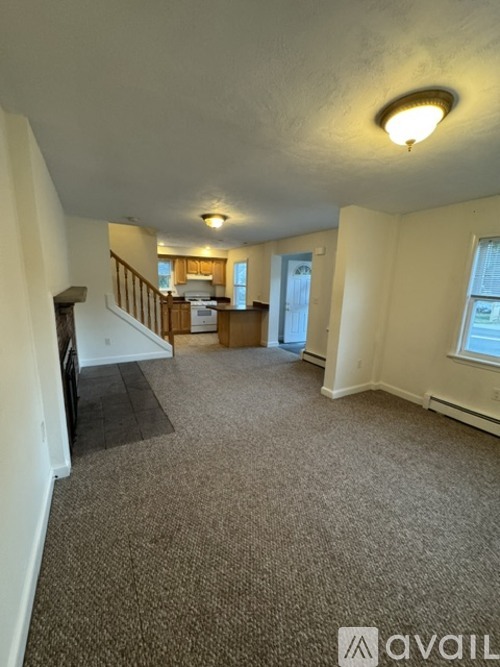 A carpeted room with a staircase leading to the second floor.