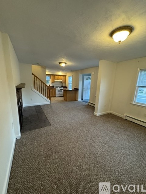 A carpeted room with a staircase leading to the second floor.