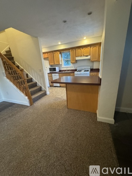 A carpeted room with a staircase leading to the upper floor.