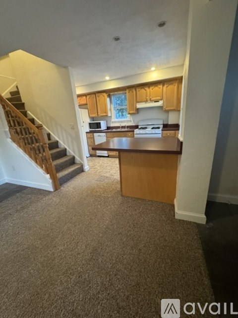 A carpeted room with a staircase leading to the upper floor.