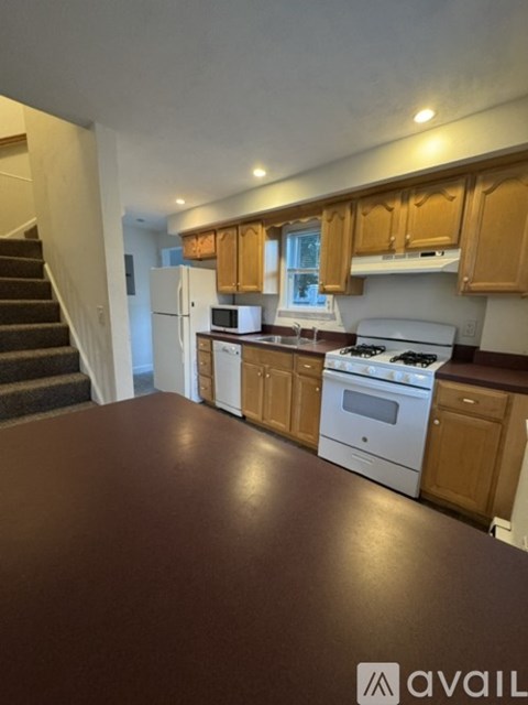 A kitchen with brown flooring and wooden cabinets.