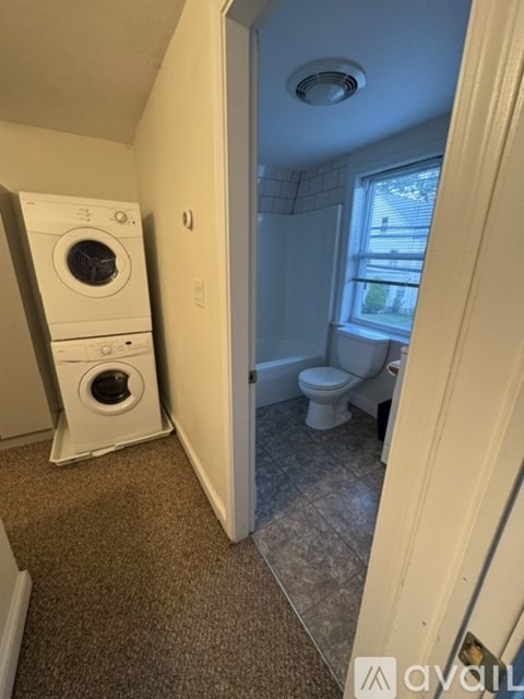 A bathroom with a washer and dryer stacked on top of each other.