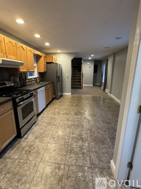 A kitchen with tile flooring and wooden cabinets.