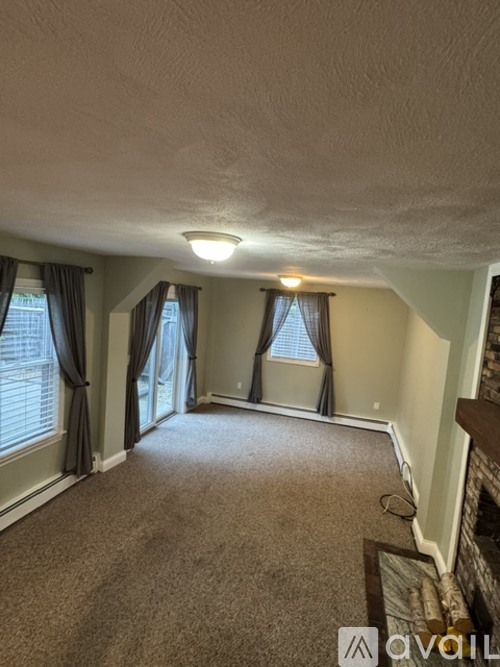 A living room with a carpeted floor and a fireplace.