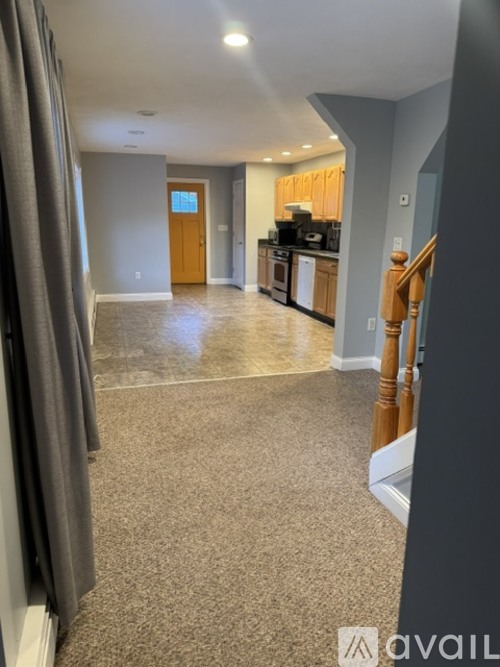 A spacious room with a carpeted floor and a wooden staircase.