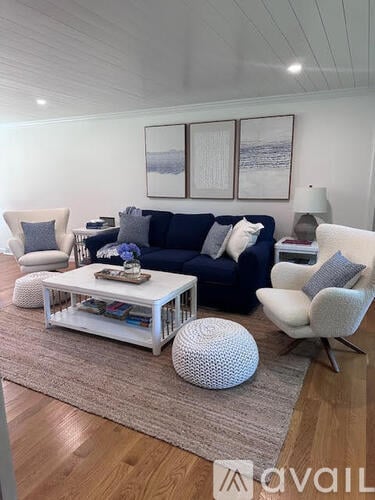 A living room with a blue couch, a white chair, and a white coffee table.