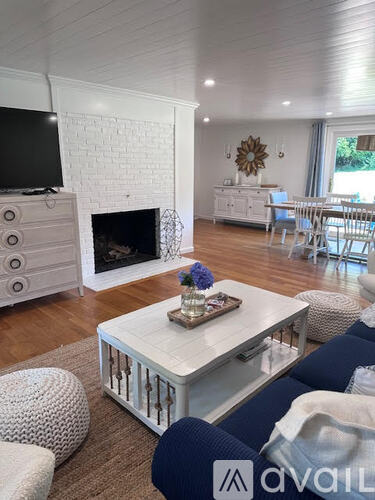 A living room with a white brick fireplace and a television mounted above it.