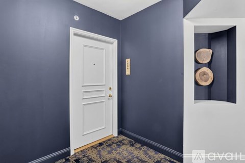 A white door with a gold handle is in a room with dark blue walls.