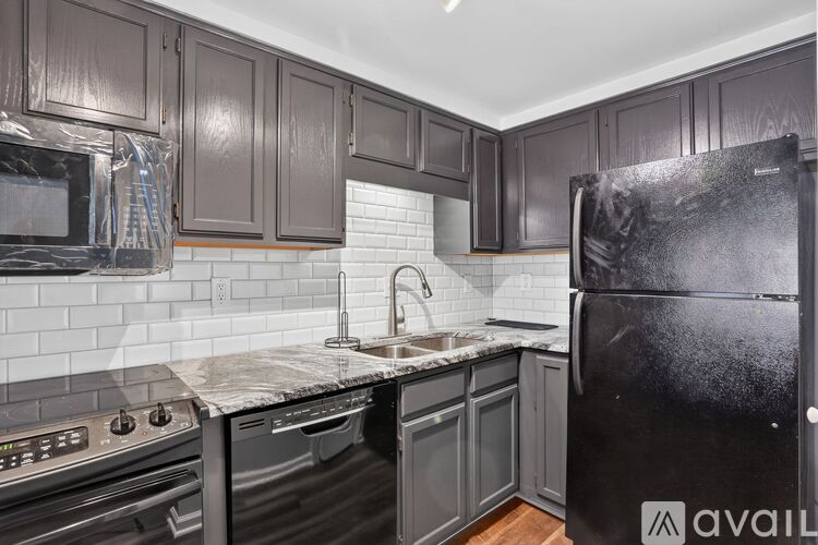 A kitchen with black cabinets and a black refrigerator.