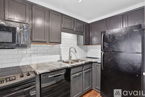 A kitchen with black cabinets and a black refrigerator.