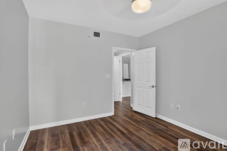 A room with wooden floors and white walls, with a doorway leading to another room.